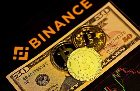 Three bitcoins on top of a $50 bill with the binance logo.