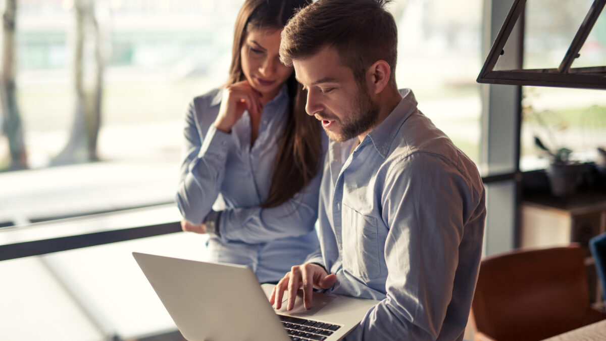 Two professionals collaborating on a laptop, discussing content syndication strategies for enhanced digital marketing reach and audience engagement.