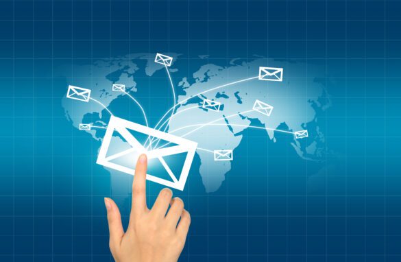 Hand Pressing A Digital Envelope Icon With Email Messages Spreading Globally On A World Map Background.